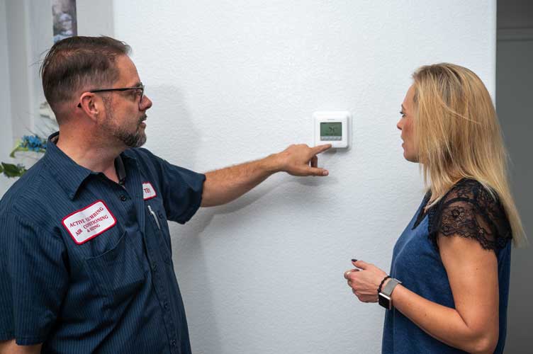 Technician Explaining Thermostat To A Woman